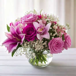 Pink and purple bouquet of roses and lilies in a clear glass vase