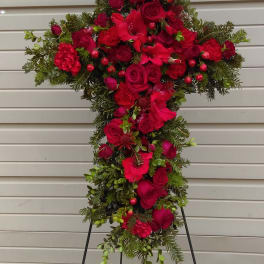 Cross-shaped floral spray with red roses and carnations on a stand