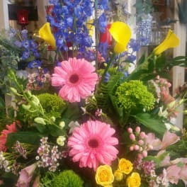 Mixed bouquet with pink gerberas, blue delphinium, yellow calla lilies, and roses