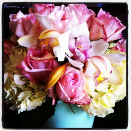 Pink roses and white orchids in a light blue vase