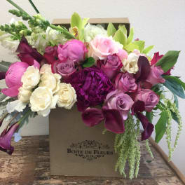 Mixed pink, white, and purple flowers arranged in a box