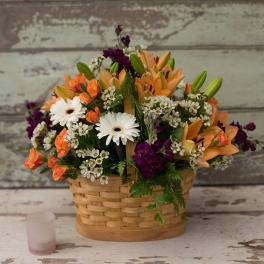 Basket arrangement of orange lilies, white daisies, and purple flowers