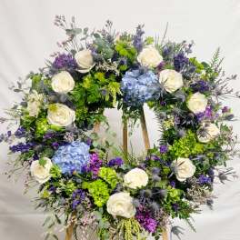 Large floral wreath with white roses, blue hydrangeas, and purple flowers