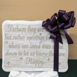 White memorial plaque with a purple ribbon bow on a stand
