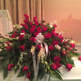 Large red rose casket spray with white ribbon and orchids