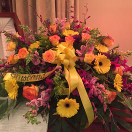 Large floral spray with yellow ribbon and mixed pink, orange, and yellow blooms