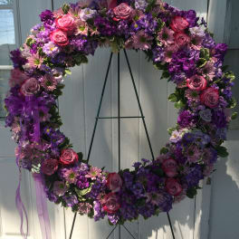 Heart-shaped floral wreath with pink and purple flowers on a stand