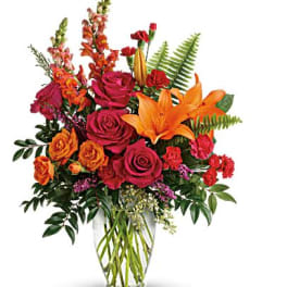 Bouquet of orange lilies and red roses in a clear glass vase