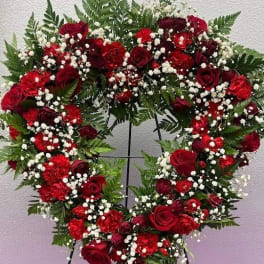 Heart-shaped wreath of red roses and white baby's breath on a stand