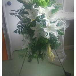 Standing floral spray with white lilies and greenery on a metal easel