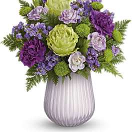 Purple and green floral arrangement in a ribbed glass vase