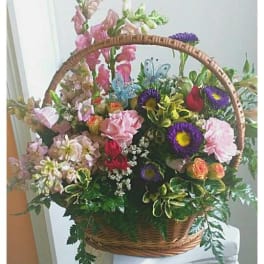 Basket arrangement of mixed pink, purple, and orange flowers
