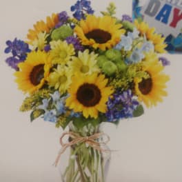 Sunflower bouquet in a clear glass vase with blue and purple flowers