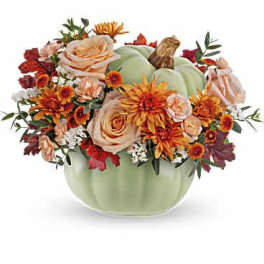 Pumpkin-shaped floral arrangement in a green container with orange and peach blooms