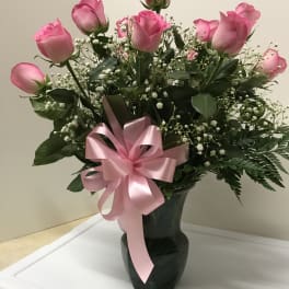 Pink roses in a dark vase with a pink ribbon bow