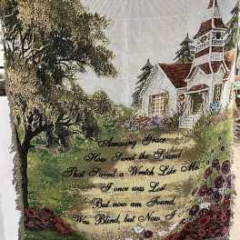 Decorative woven throw with a house, trees, and floral border