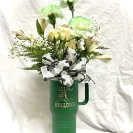 White and pale green flowers in a green travel tumbler with a bow