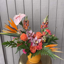 Bright tropical bouquet with roses, orchids, and bird of paradise in a yellow vase