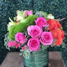 Bouquet of pink and orange roses in a green glass vase