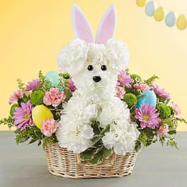 White bunny centerpiece in a wicker basket with pastel flowers and eggs