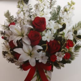 Bouquet of red roses and white lilies in a glass vase with a red ribbon
