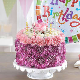 Pink and purple flower cake with birthday candles and a balloon