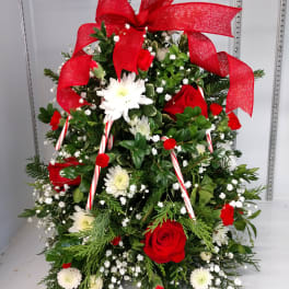 Christmas floral arrangement with red roses, white daisies, and a large red bow