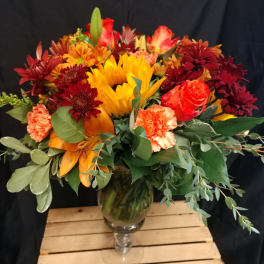 Mixed bouquet in a glass vase with sunflowers, roses, and carnations