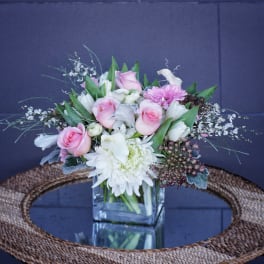 Pink and white flower arrangement in a square glass vase