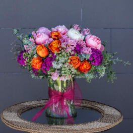 Pink and orange mixed bouquet in a glass vase with a magenta ribbon