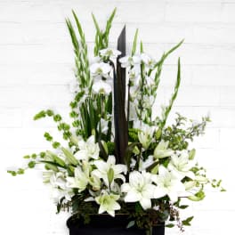 White lilies and orchids arranged in a tall black container