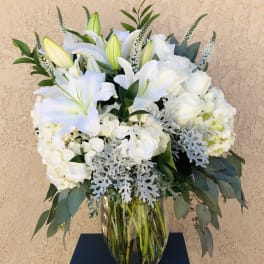 White lilies and roses arranged in a glass vase