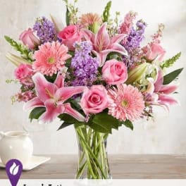 Pink roses, lilies, and gerbera daisies in a clear glass vase