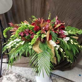 Large floral spray with red roses, burgundy orchids, and white blooms on a pedestal