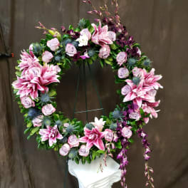 Circular floral wreath with pink lilies and lavender roses on a stand