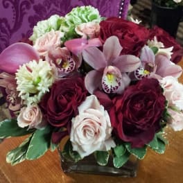 Bouquet of pink and burgundy flowers in a square glass vase
