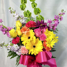 Bright mixed bouquet with yellow gerbera daisies and pink roses, tied with a hot pink ribbon