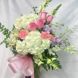 Bouquet of pink roses, white hydrangeas, and lavender flowers in a glass vase