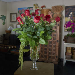 Tall vase arrangement of red roses with cascading greenery