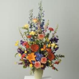 Tall mixed flower arrangement in a pale vase