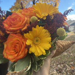 Handheld bouquet of orange roses and yellow gerbera daisies