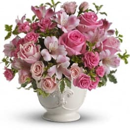 Pink roses and alstroemeria arranged in a white ceramic urn-style vase
