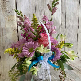 Basket arrangement of pink and purple flowers with a blue ribbon