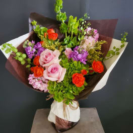Bouquet of pink and orange roses with purple blooms and green filler