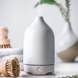 White ceramic essential oil diffuser emitting mist on a spa-like counter