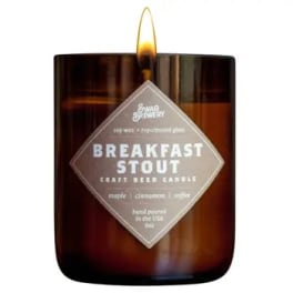 Brown glass jar candle labeled Breakfast Stout with a lit flame