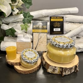 Candles and fragrance products arranged on wood slices with faux flowers in the background