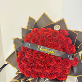 Large bouquet of red roses with a black ribbon reading "I love you"