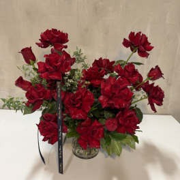 Red roses arranged in a clear glass vase with a black ribbon