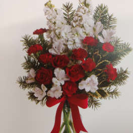 Red roses and white flowers in a clear vase with a red ribbon